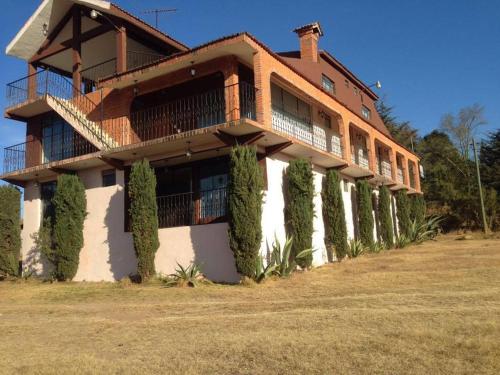 un bâtiment avec des arbres devant lui dans l'établissement Hotel Lienzo Charro 1, à Huasca de Ocampo