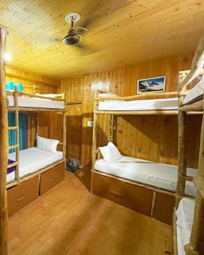 a room with three bunk beds in a cabin at Mazel Tov Stays, Tirthan Valley in Gushaini