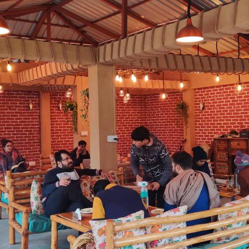 a group of people sitting at tables in a room at Mazel Tov Stays, Tirthan Valley in Gushaini