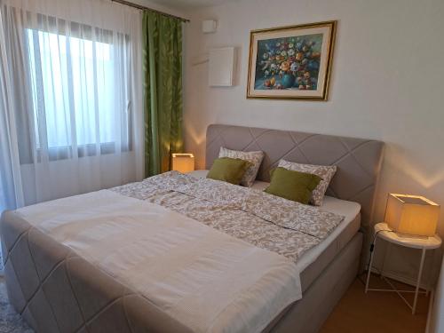 a bedroom with a large white bed with green pillows at Ferienhaus Weingarten Eisenberg in Vaskeresztes