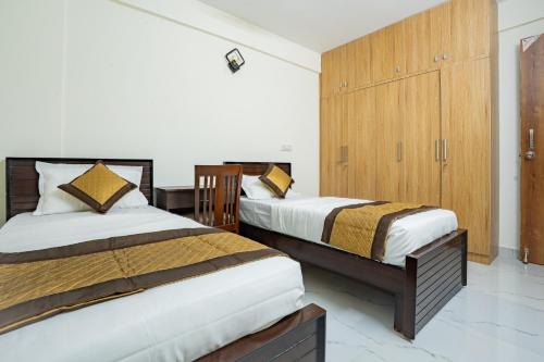 a bedroom with two beds and a wooden cabinet at Odilia Apartelle in Bangalore