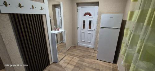 a hallway with a white door and a refrigerator at Levente vendégház in Szilvásvárad