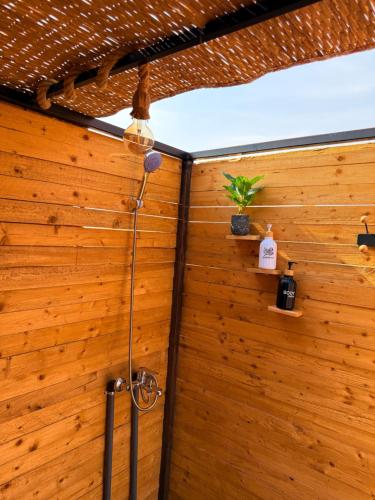 a shower in a room with a wooden wall at Night Stars Camp in Badīyah