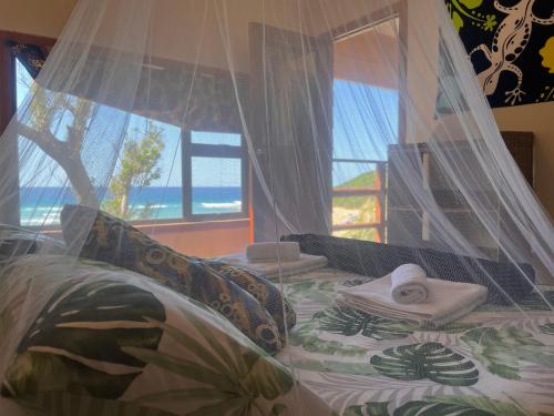 a bedroom with a bed with a view of the ocean at Bamboo Room in Ponta do Ouro