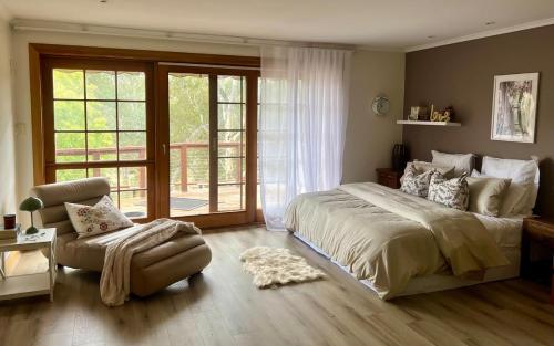 a bedroom with a large bed and a chair at Bodhi Valley BnB in Golden Grove