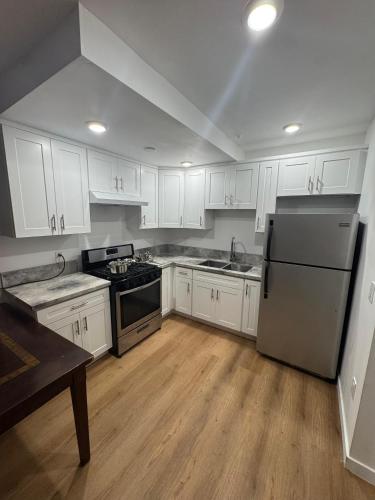 a kitchen with white cabinets and a stainless steel refrigerator at Vernon Vibes in Los Angeles