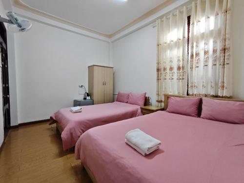 two beds in a room with pink sheets at Guesthouse Big Lucky in Da Lat