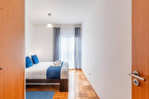 a bedroom with a bed with blue pillows and a window at Sapphire Scape Near Airport Madeira Santa Cruz in Gaula