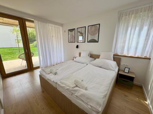 a bedroom with a large bed with white sheets at Vinopool Suites Badacsony in Badacsonytomaj