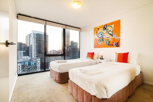 two beds in a room with a large window at Exclusive Stays - Southpoint in Melbourne