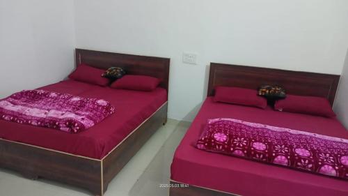 two beds in a room with purple sheets and pillows at Hotel Mahadev in Sonprayag