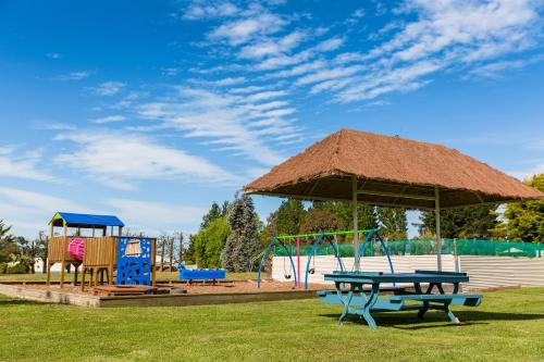 a park with a picnic table and a playground at North South Holiday Park in Christchurch