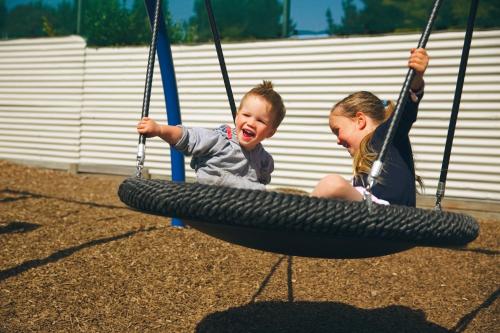 two children playing on a tire swing at North South Holiday Park in Christchurch