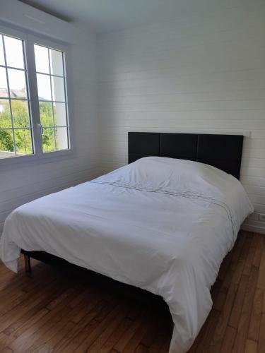 a bedroom with a large white bed with a black headboard at Maison de Crozon in Crozon