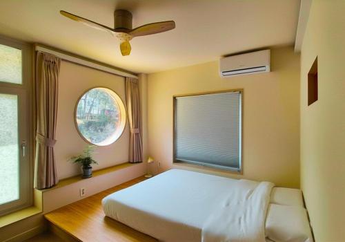 a bedroom with a bed and a window with a fan at SoSi Stay in Seoul