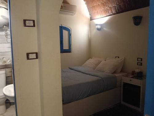 a small bedroom with a bed and a bathroom at malindy KA nubian houseماليندى كا in Aswan