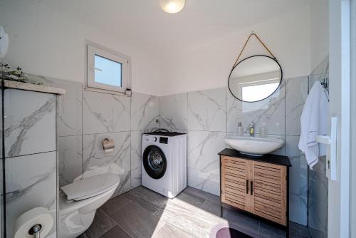 a bathroom with a sink toilet and a washing machine at Holiday House Roza in Vela Luka