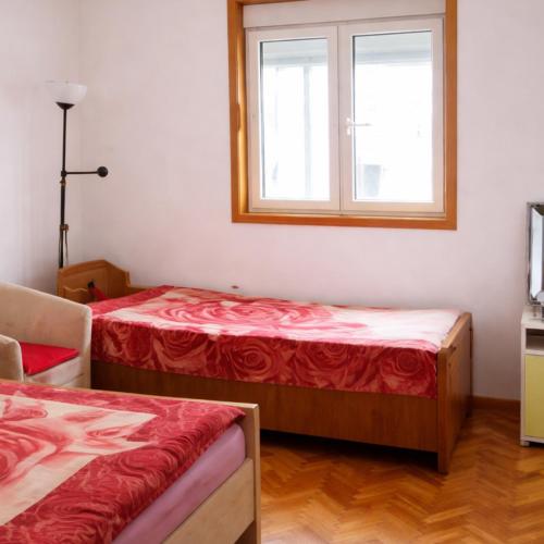 two beds in a room with a window at Apartments Zenit in Kotor