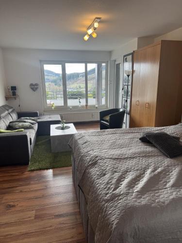 a bedroom with a bed and a couch and a window at Ferienwohnung Inge Steinrücken in Winterberg
