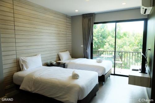 two beds in a hotel room with a window at C Cha-Am Hotel in Cha Am