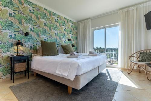 a bedroom with a large bed and a large window at Quinta do Pedro in Luz de Tavira