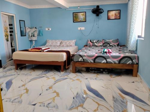 two beds in a room with blue walls at Auro Delight - Near Auroville in Pondicherry in Villupuram