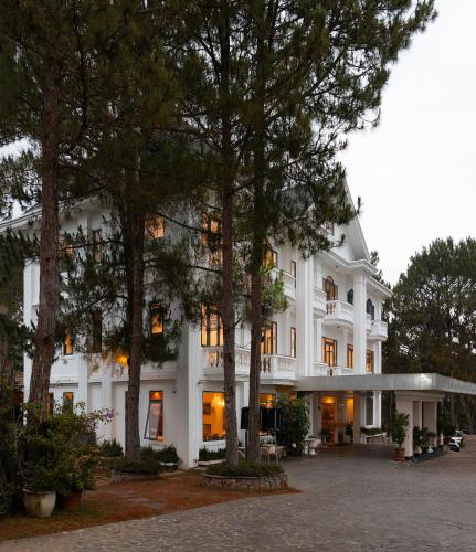 a large white building with trees in front of it at Rung La Kim Resort in Da Lat