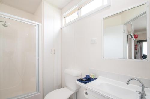 a bathroom with a toilet and a sink and a mirror at Warragul Gardens Holiday Park in Warragul