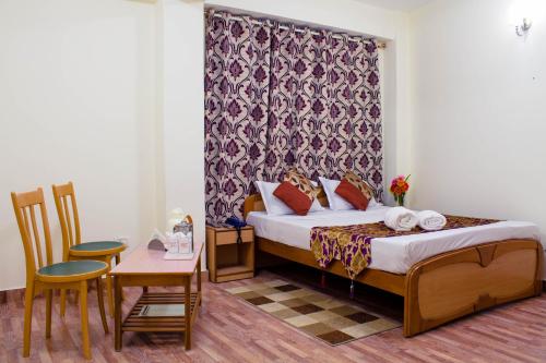 a hotel room with a bed and a table and chairs at Hotel Renam in Gangtok