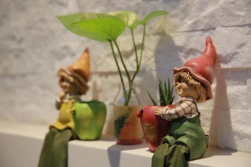 a group of figurines sitting on a shelf with a plant at Enjoy Homestay in Tainan