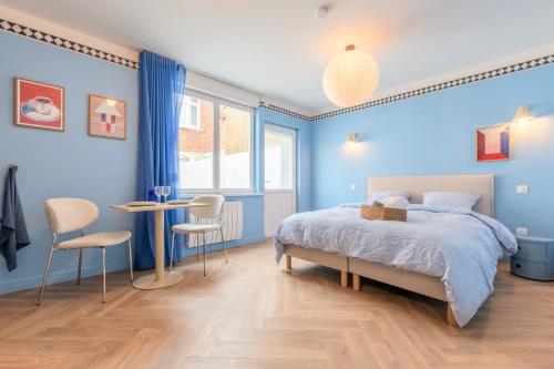 a blue bedroom with a bed and a table and chairs at Le Cottage du Louvre in Lens