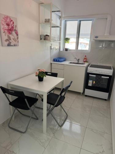 a white kitchen with a white table and chairs at Sun Beach Apartment in Anavyssos