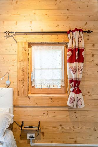 a bedroom with a window in a wooden wall at Blizzard apartments Kevin in Arabba