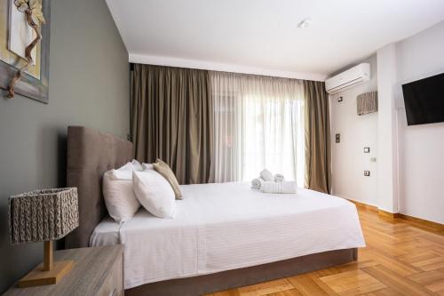 a bedroom with a large white bed with a window at Charming Maisonette In Southern Suburbs in Athens