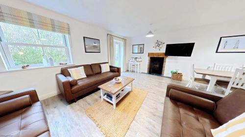 a living room with couches and a table at Old England Cottage - Part of the The Bay Filey Holiday Village with pool, gym and direct beach access, pub, restaurant, tennis and meadows walks in Filey