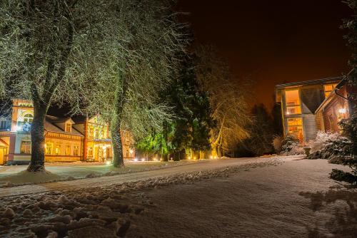 a snowy street at night with trees and buildings at Marcienas Muiza & SPA in Mārciena