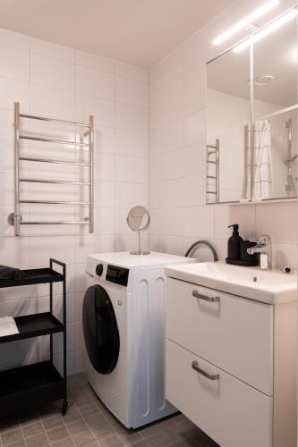 a white kitchen with a washing machine and a sink at Guestly Homes - Central Premium Suite 1BR in Västerås