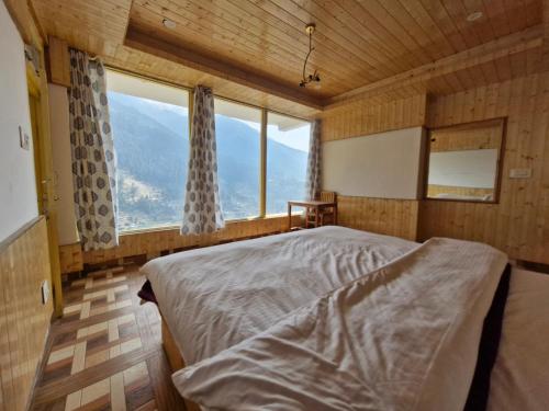 a bedroom with a bed and a large window at Jibhi Emberwood in Jibhi