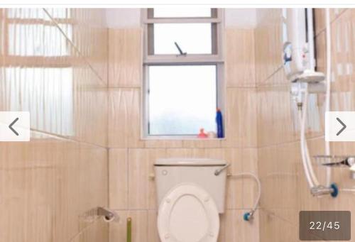 a bathroom with a toilet and a window at Roje's Oasis in Jinja