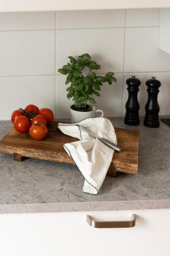 a cutting board with tomatoes and a knife on a counter at Guestly Homes - Central Premium Studio in Västerås