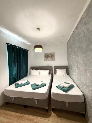 two beds in a small room with green curtains at Apartman VUKAN in Budva