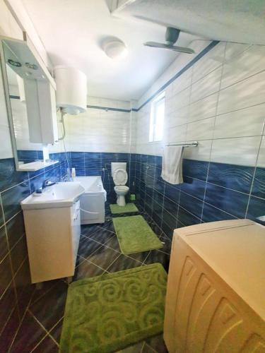 a blue tiled bathroom with a toilet and a sink at Villa Nature in Hadžići