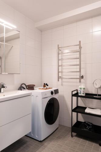 a white bathroom with a washing machine and a sink at Guestly Homes - Central Smart Studio in Västerås
