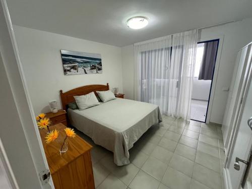 a bedroom with a bed and a table with flowers on it at C&M Dream House in Morro del Jable