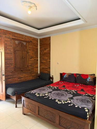 a bedroom with a bed and a bench in it at Rumah Ukhi Guest House in Yogyakarta