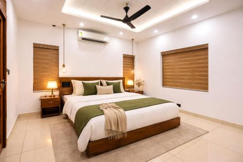 a bedroom with a large bed and a ceiling fan at THE iVORY VILLA in Kottayam