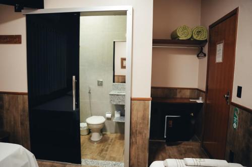 a bathroom with a toilet and a glass door at Candeias Hotel in Batatais