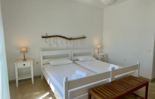 a bedroom with a white bed with two tables and a bench at Piperi On The Rocks in Naousa