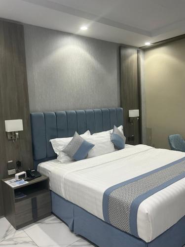 a bedroom with a large bed with a blue headboard at فندق اجنحه البيداء فرع2 AlBaydaa Suites Hotel Branch in Medina