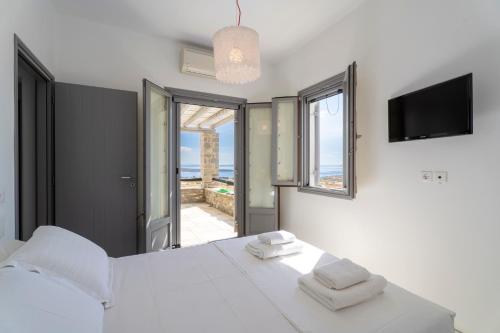 a bedroom with a white bed and a view of the ocean at Infinity Blue - Villa A in Aspro Chorio Paros